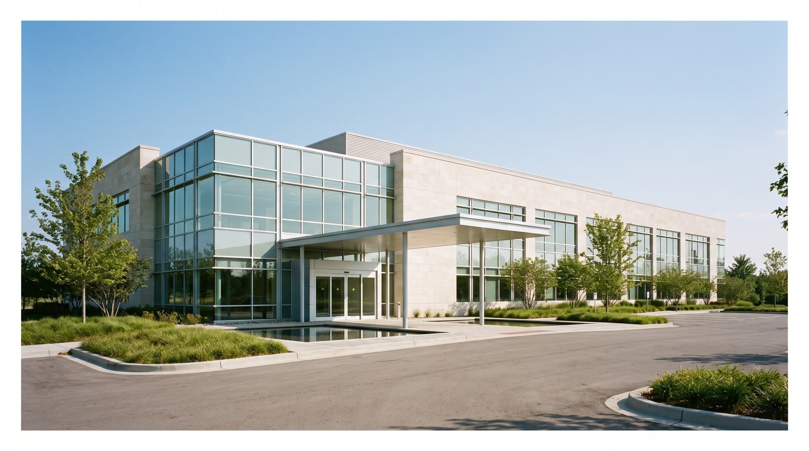 The exterior of a low-rise research center with a glass and pale stone facade and landscaped grounds.